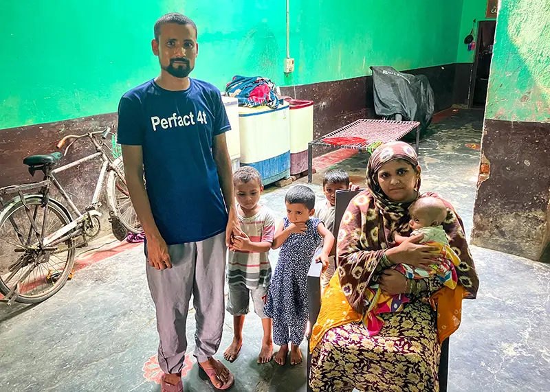 A man and woman pose with three small children and a baby inside their home.