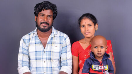 A little boy sits with his mother and father.